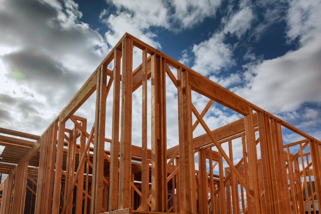 New residential construction house wood building frame against a blue sky.